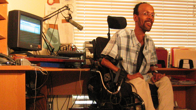 A disabled man in a wheelchair in his home radio studio.