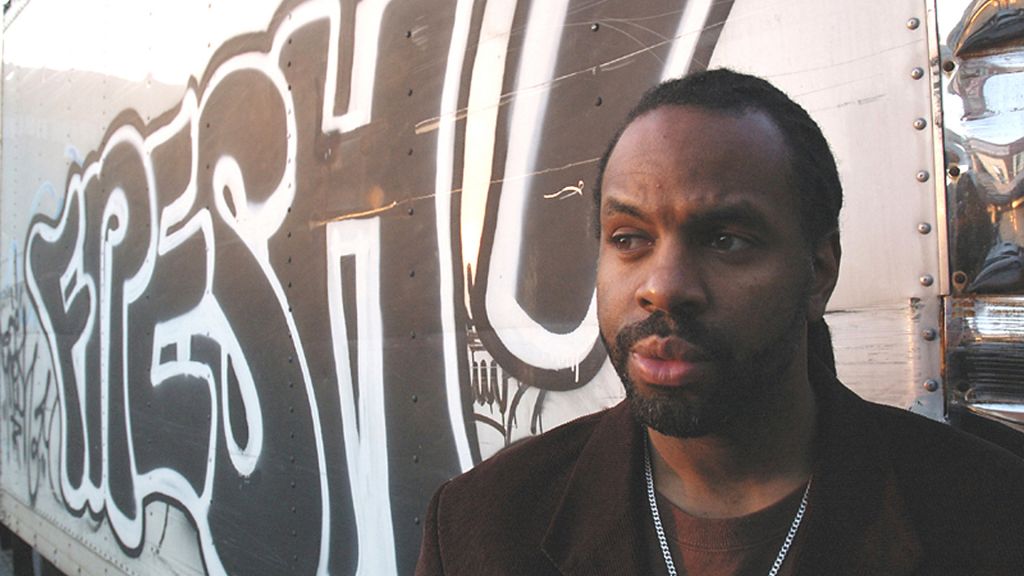 A man stands in front of a graffiti wall