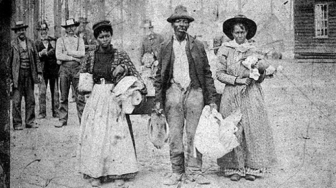 A black family walks down the road after being forced from their home in 19th century America.