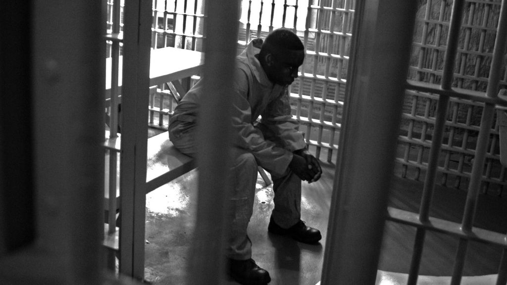 A man sits in a jail cell