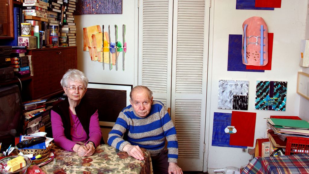 Herb and Dorothy Vogel sitting at the kitchen table in their apartment surrounded by art