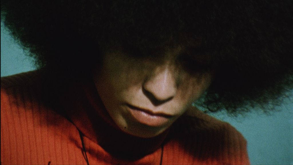 Angela Davis with Afro and orange sweater.