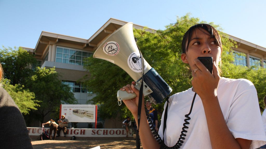 Young girl holds megaphone to her mouth.