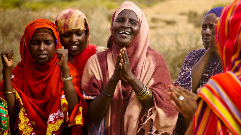 Smiling women in colorful clothing.