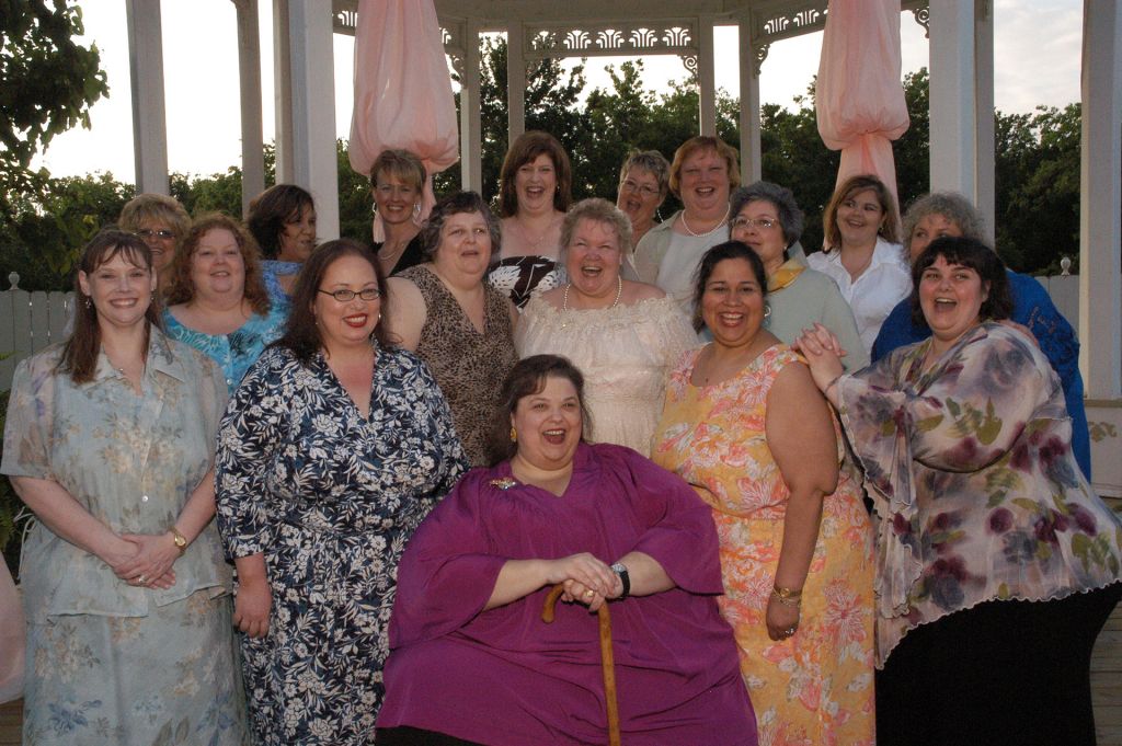 Overweight women gather under a gazebo.