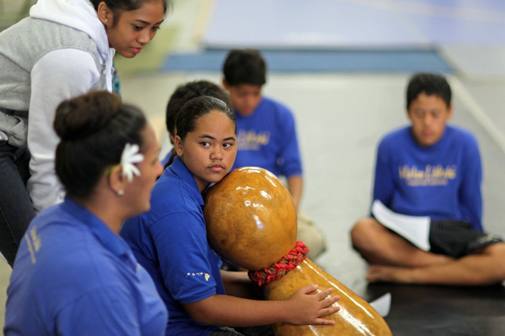 Ho’onani holds Hawaiian drum while listening to her teacher, Hina.