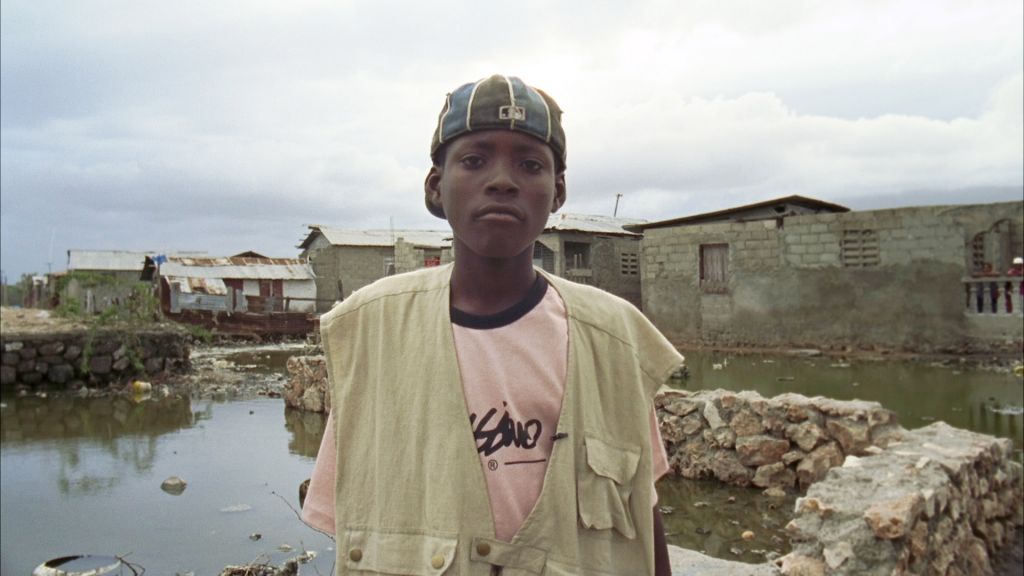 A Haitian boy stands in a water-logged slum.