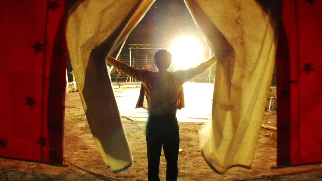 A circus performer casts aside the curtains before entering the ring.