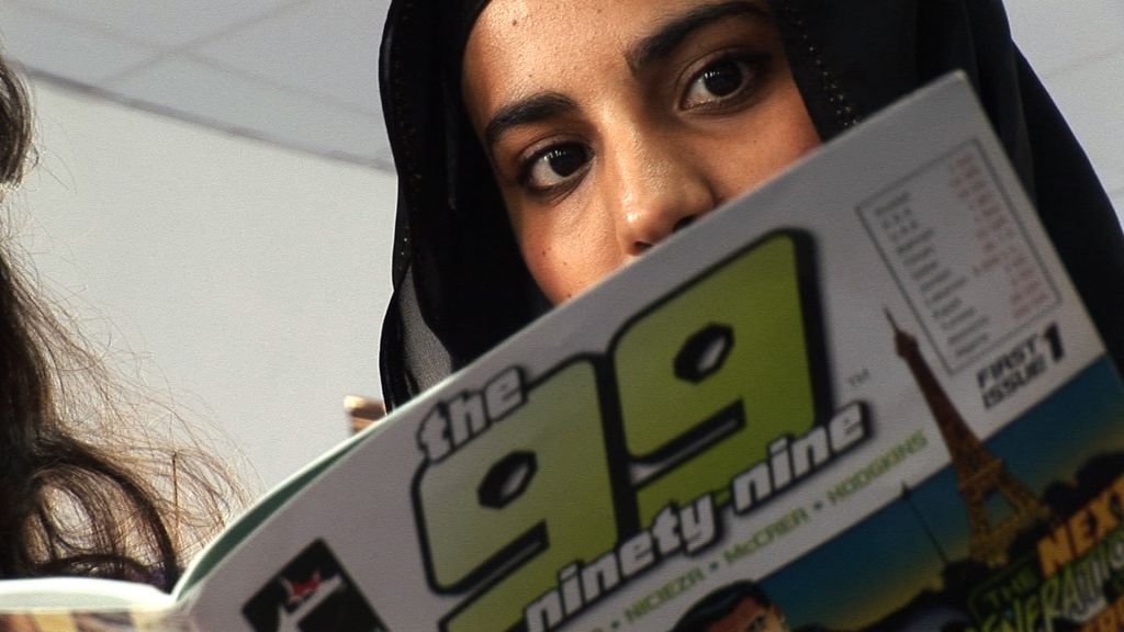 A woman in headscarf reads the 99 comic book.