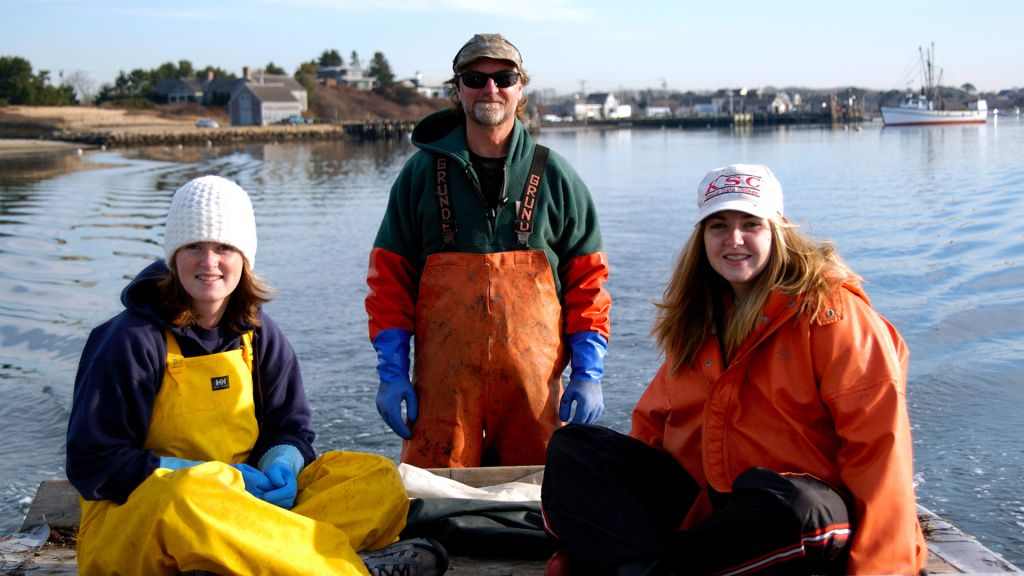 Two women and a man in a boat on the water in fishing gear