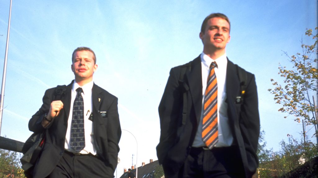 Two young men in suits walk down the street