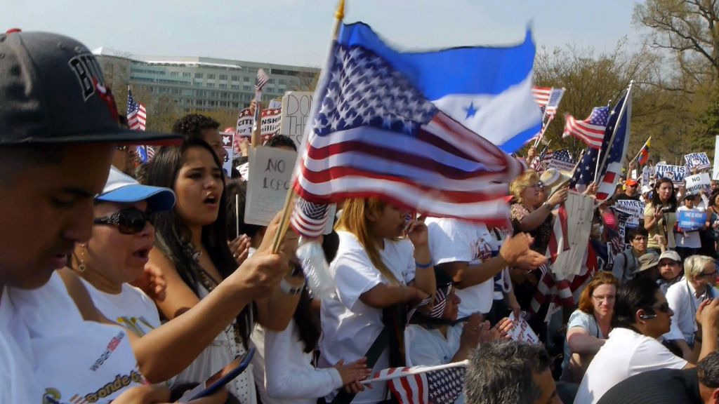 Immigration protestors in Washington D.C. wave flags of America and Honduras.