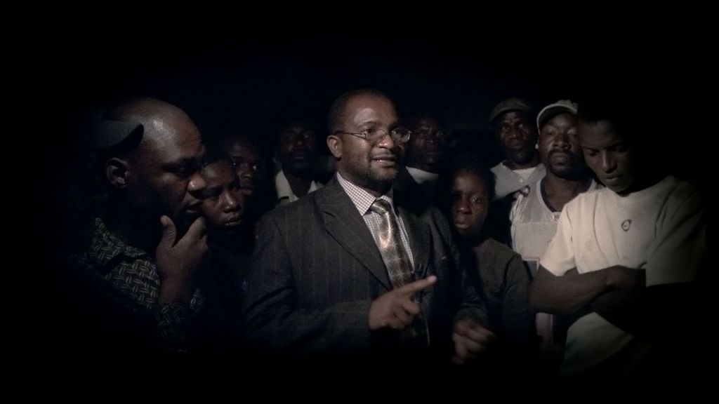 A politician speaks to a crowd of men in a Zimbabwe village.