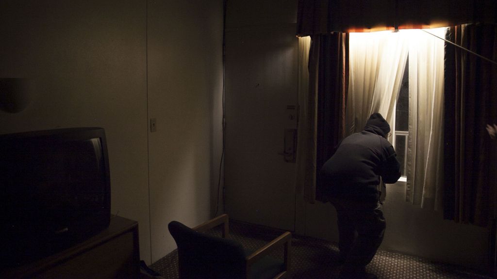 FBI informant Saeed "Shariff" Torres peers out a motel room window at night