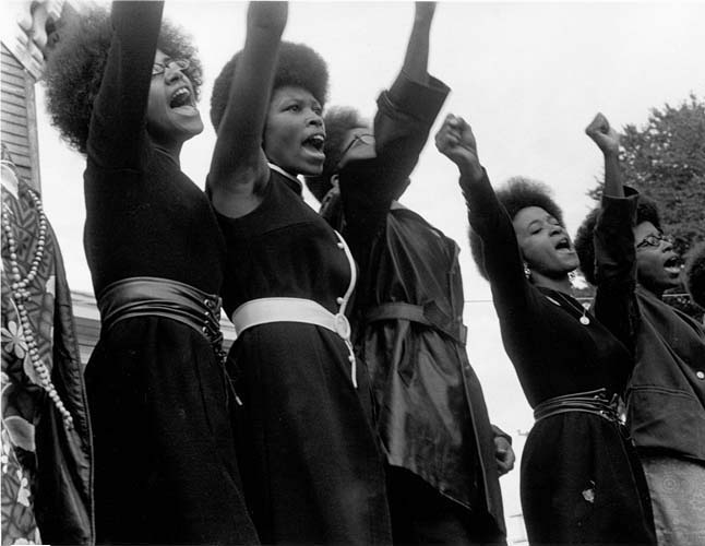 Woman dressed in all black with right fists in the air