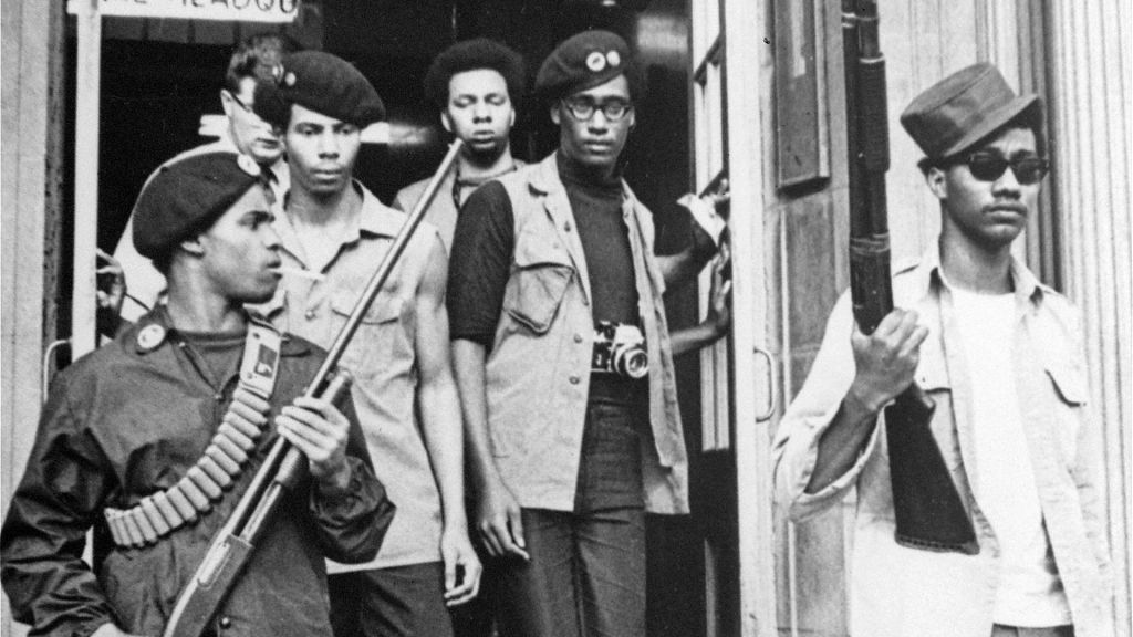 Black Panthers exiting building armed with rifles.