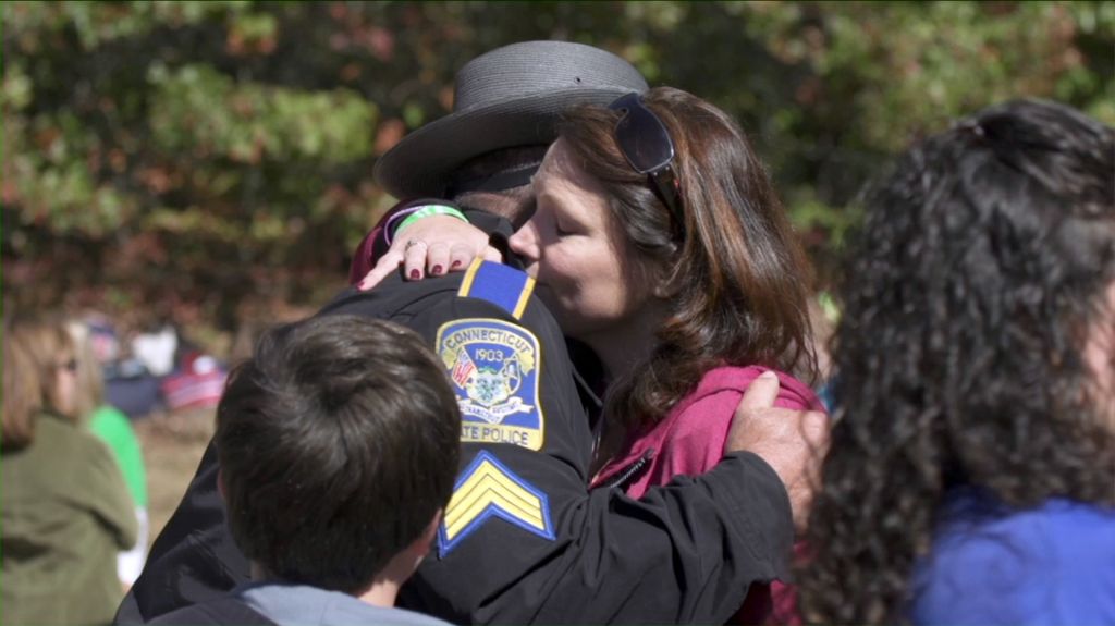 A mother who lost a child in the Sandy Hook Elementary mass shooting in Newtown, CT in December 2012 embraces a state police officer.