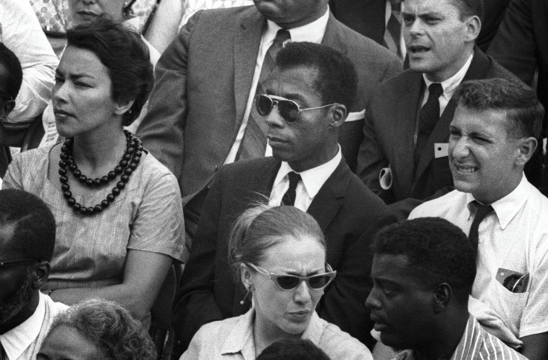 Malcom X sitting in a crowd looking off screen