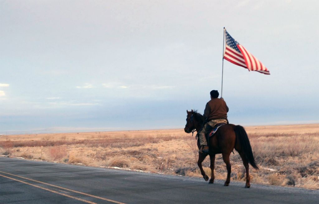 scene from No Man's Land, member of armed standoff in oregon riding horseback with American flag