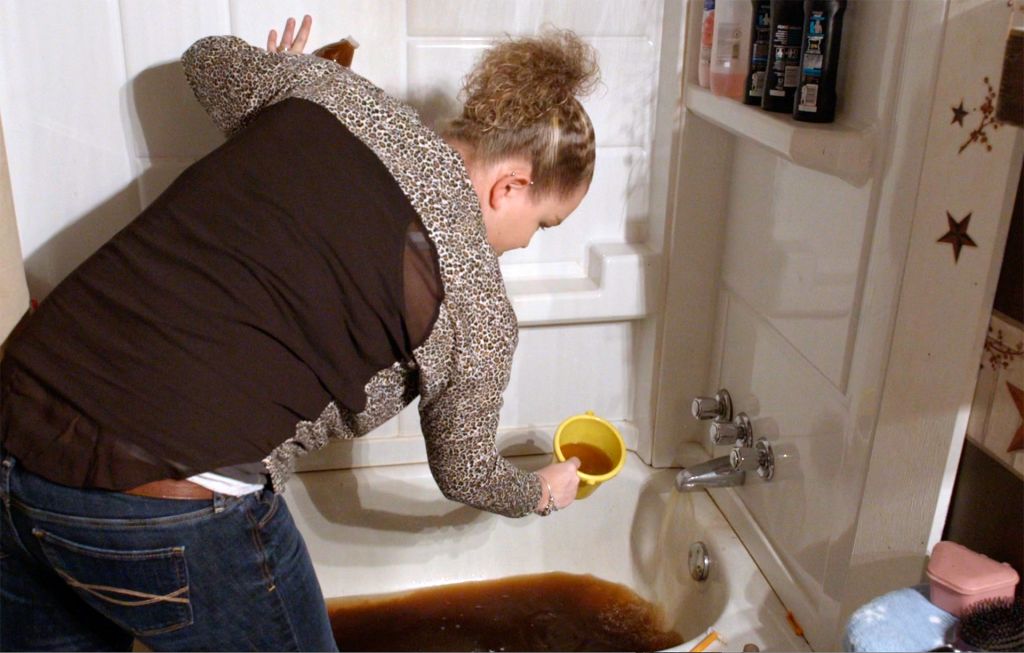 A woman demonstrates the polluted tap water in her home in West Virginia after chemical spill, in What Lies Upstream