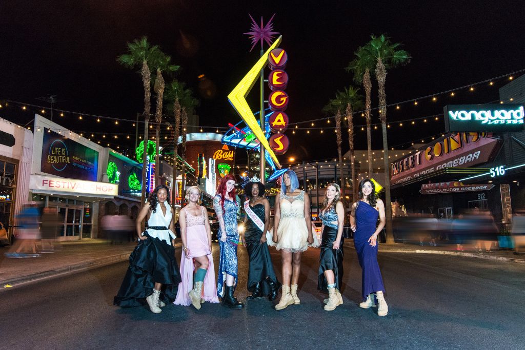 The women of Served Like a Girl dressed in pageant dresses with combat boots, on Vegas strip at night