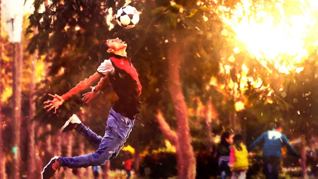 Man leaping while heading a soccer ball, in a park; creative commons image via PixaBay