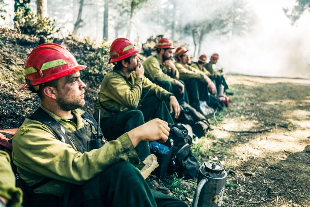 Young male firefighters at rest in a forest during a wildfire