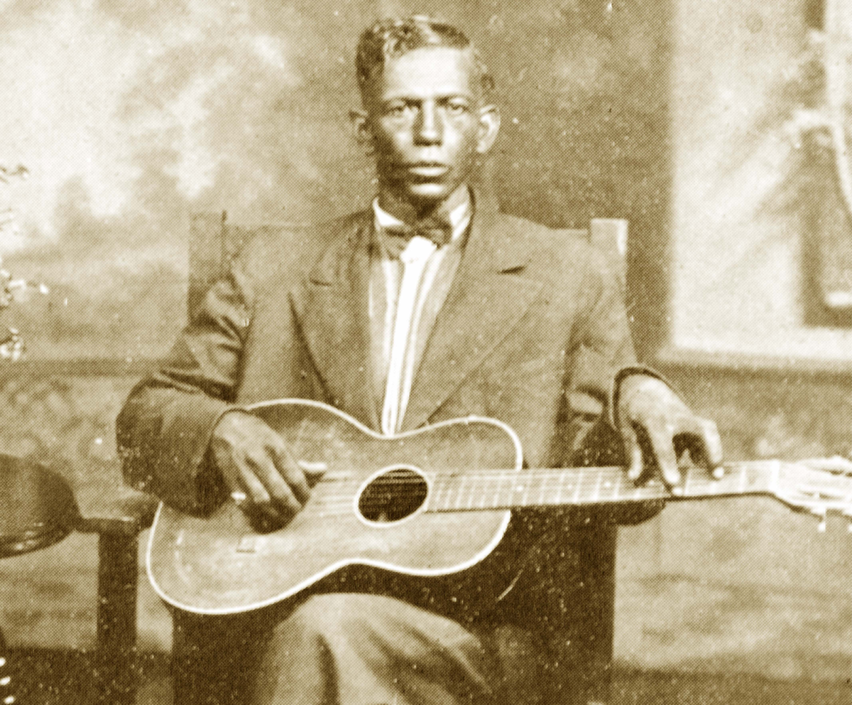 Man (Charley Patton) sitting for a portrait with a guitar in his lap