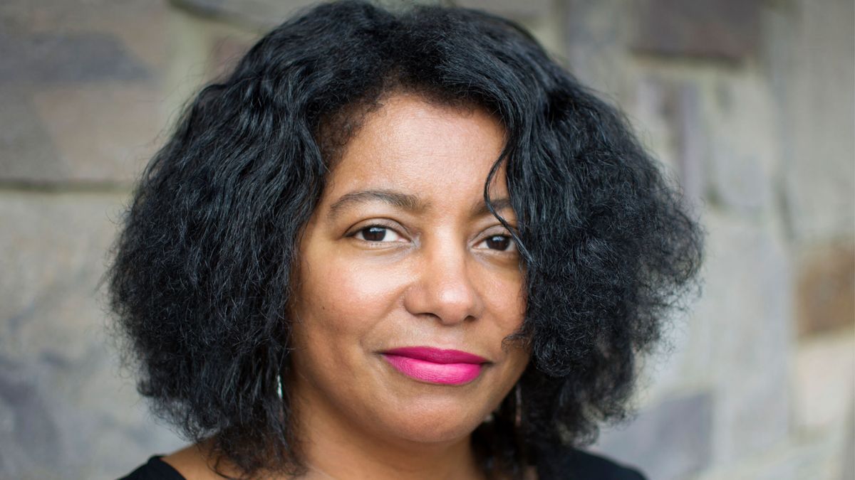 Headshot of filmmaker Jacqueline Olive, a woman with medium-dark skin tone and shoulder-length dark hair. She wears pink lipstick.