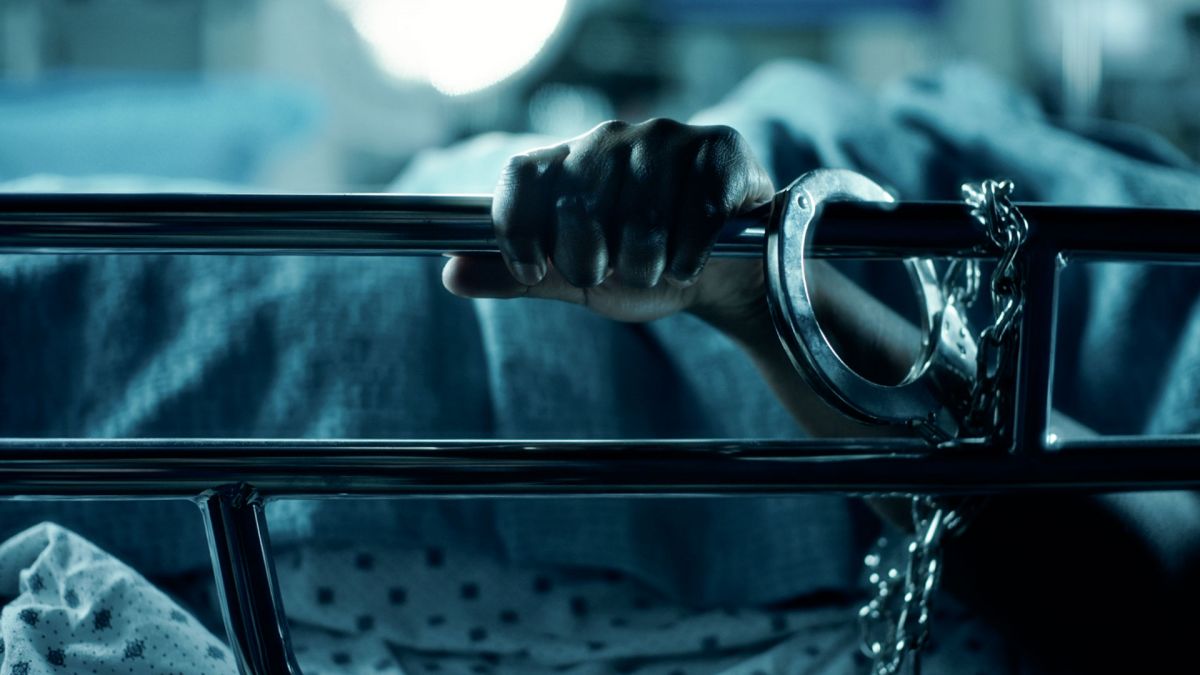 A woman's hand is handcuffed to a hospital bed.