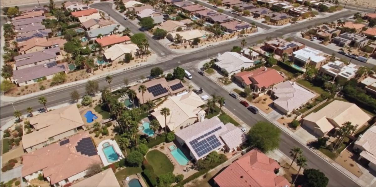 A sunny, overhead view of homes in a Las Vegas suburb, some with pools and solar paneled roofs.