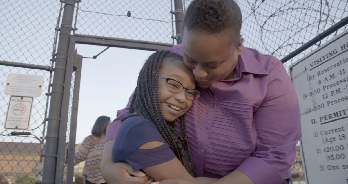 Woman hugging her daughter just outside prison gates