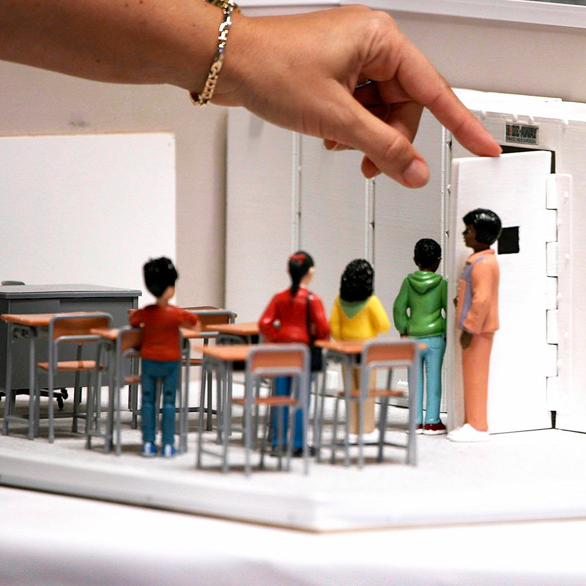 Mini model of a classroom safety drill with figurines of a teacher and students leaving their classroom in a line.