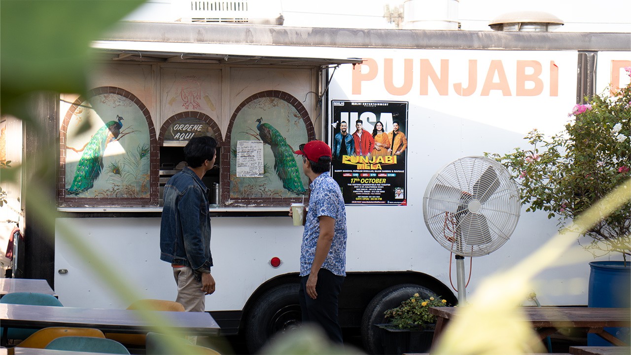 Two men standing outside building that says Punjabi