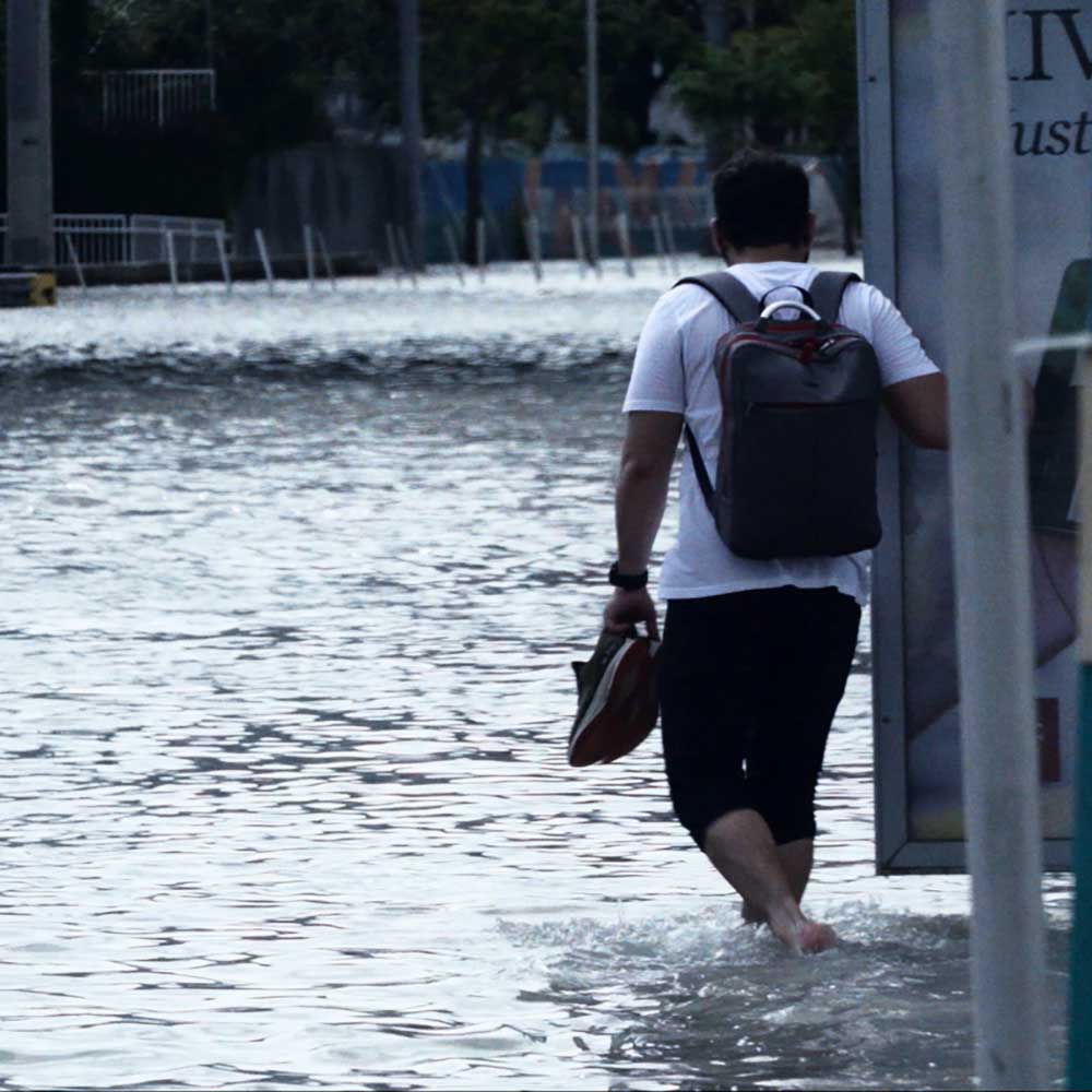 A flooded Miami street after a hurricane, a man walks through the waters. Photo Credit (photographer): Hector David Rosales