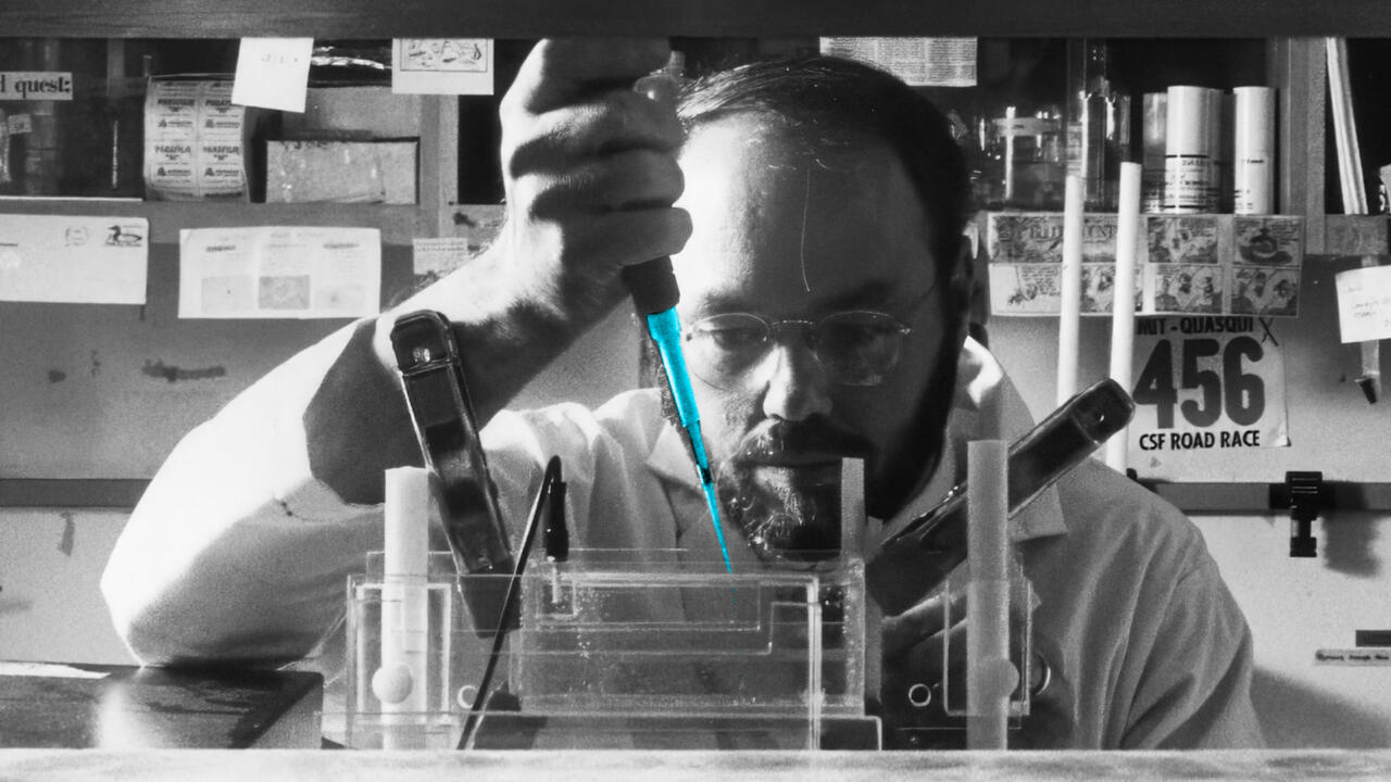Phil Sharp using a pipet in a lab in black and white - the liquid in the pipet bright blue and focal point of image