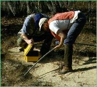 Two men operating the burrowcam into a tortoise burrow